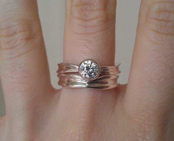A curved wedding band complementing a stunning moissanite engagement ring. Available from alchemyhouse on Etsy 